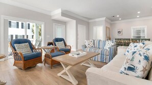 A spacious living room with wicker furniture, a light-colored sofa, and a striped couch. - ⚓ Heated pool, Hot Tub, Games & More, 5 min> walk to beach!⚓🐕🏖🌅 (Holmes Beach)
