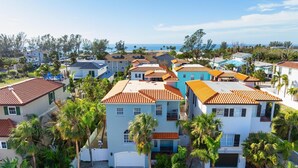 A coastal residential area with houses featuring red-tiled roofs and white walls, surrounded by palm trees and a clear view of the ocean. - ⚓ Heated pool, Hot Tub, Games & More, 5 min> walk to beach!⚓🐕🏖🌅 (Holmes Beach)