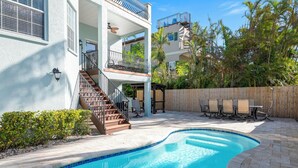 A two-story building with a swimming pool, outdoor seating, and a wooden fence. - ⚓ Heated pool, Hot Tub, Games & More, 5 min> walk to beach!⚓🐕🏖🌅 (Holmes Beach)