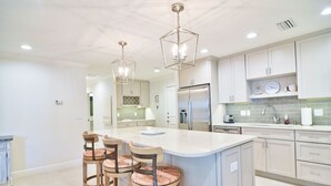 A modern kitchen with a central island, bar stools, stainless steel appliances, and pendant lighting. - Anna Maria Island Getaway (Holmes Beach)