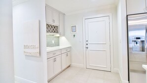 A kitchen with white cabinets, a double door, and a stainless steel refrigerator. - Anna Maria Island Getaway (Holmes Beach)