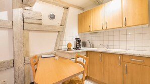 A kitchen with wooden cabinets, a white countertop, and a dining table with chairs.