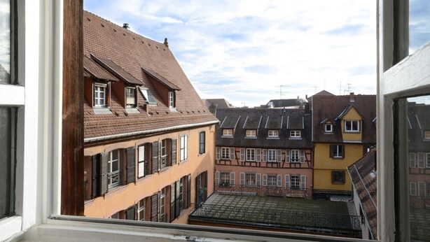 Vue d’un quartier résidentiel caractérisé par une architecture européenne traditionnelle, avec des immeubles à plusieurs étages dotés de toits à pignons et de fenêtres à volets.