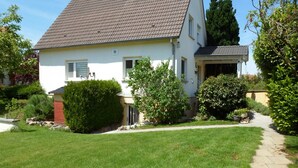 Une maison à deux étages, dotée d’un toit en pente, d’un porche à l’avant et d’une pelouse bien entretenue.