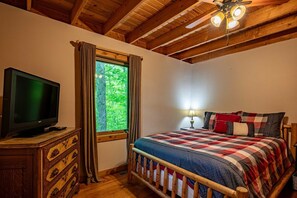 A bedroom with a bed, a television on a wooden dresser, a window with curtains, and a ceiling fan. - Evergreen Lodge Old Forge (Old Forge)