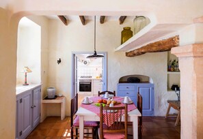 Une cuisine avec une table à manger pour deux personnes, un luminaire suspendu et un meuble bleu.