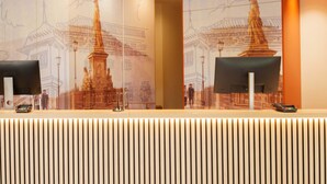 Un mostrador de recepción con un gran mural de un edificio histórico y una estatua.