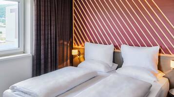 Ein Hotelzimmer mit einem Bett, einem Fenster und einer Wand mit Streifenmuster.