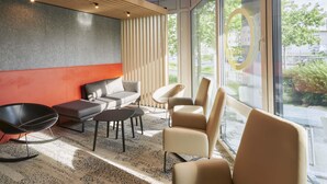 A modern interior with a sofa, chairs, a coffee table, and a large window offering a view of the outdoors. - B&B Hotel Heidelberg (Heidelberg)