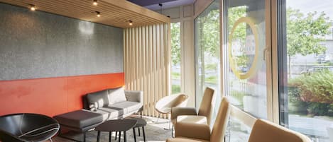 Un intérieur moderne comprenant un canapé, des fauteuils, une table basse et une grande fenêtre donnant sur l’extérieur.