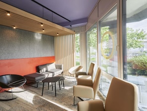 A modern interior with a sofa, chairs, a coffee table, and a large window offering a view of the outdoors. - B&B Hotel Heidelberg (Heidelberg)