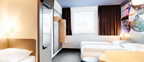 A hotel room with two beds, a desk, a chair, a small table, and a window with curtains.