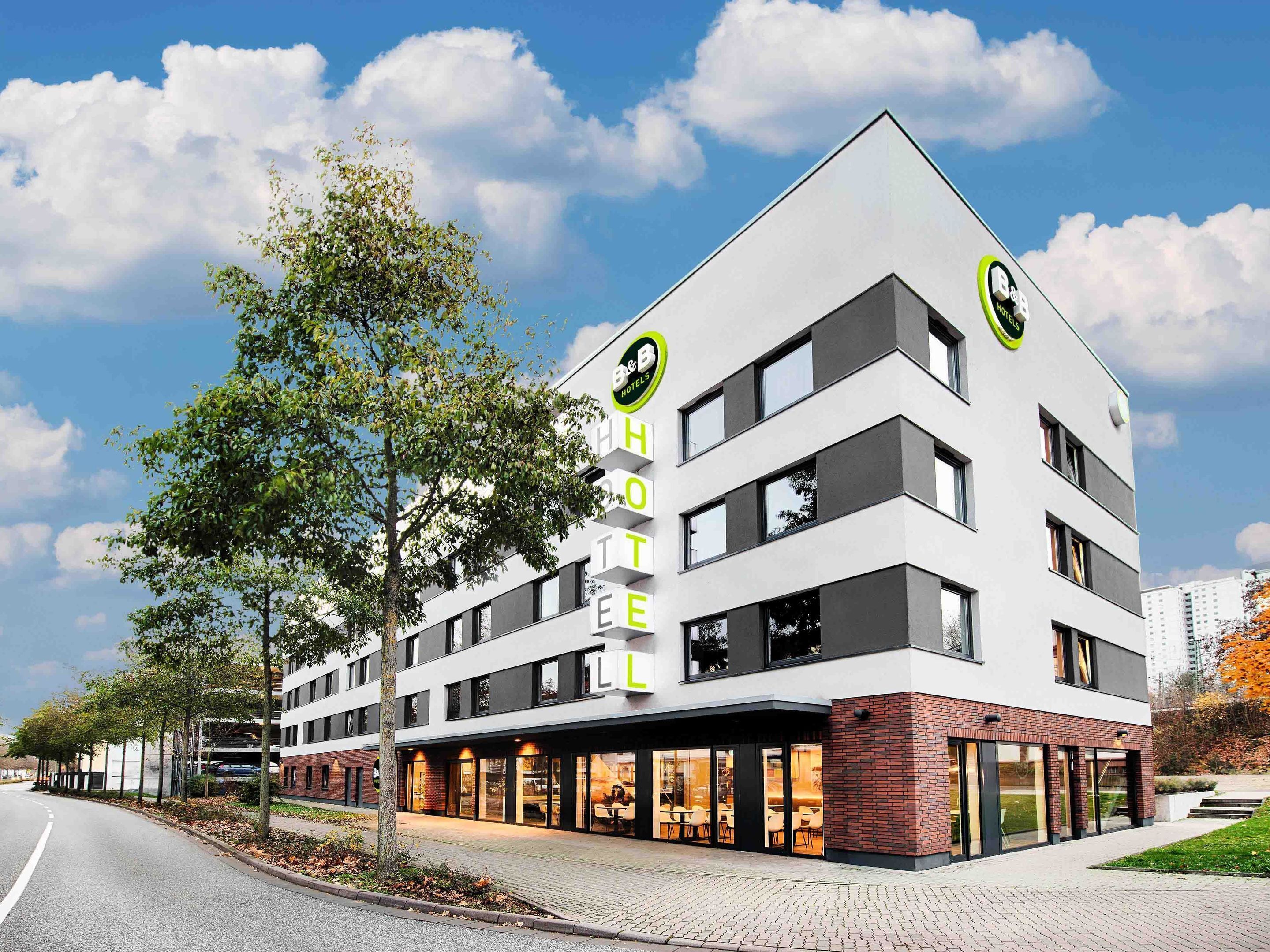 A modern hotel with a flat roof, multiple floors, and a prominent sign.