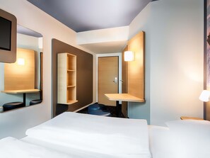 A modern hotel room with a large bed, a built-in wardrobe, a mirror, and a bedside table with a lamp. - B&B Hotel Kaiserslautern (Kaiserslautern)