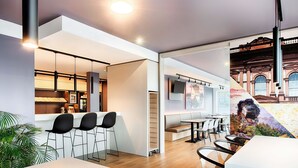 A modern interior with a bar area, seating, and a TV mounted on the wall. - B&B Hotel Kaiserslautern (Kaiserslautern)