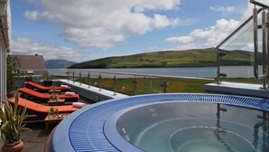 A rooftop pool area with lounge chairs and a hot tub, overlooking a lake and hills. - Dingle Skellig (Dingle)
