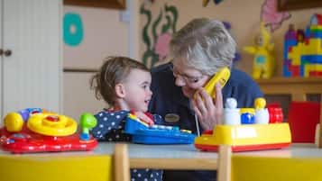 A child and an adult at a table with toys and a telephone.