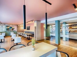 Un café moderne avec des tables blanches, des chaises noires et des lampes suspendues.