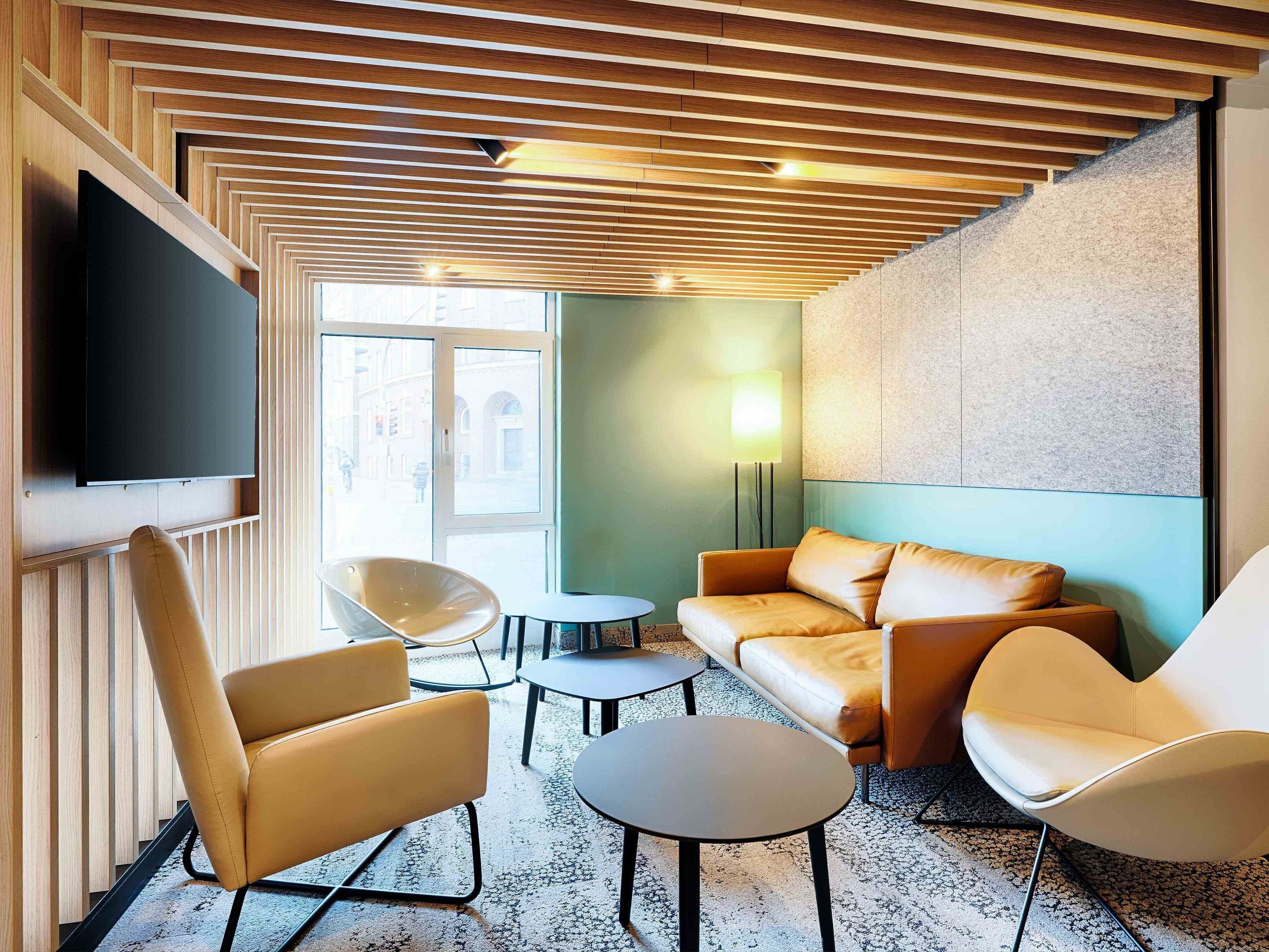 Un espace de détente moderne avec un plafond en bois, un téléviseur à écran plat, des canapés en cuir et une table ronde.