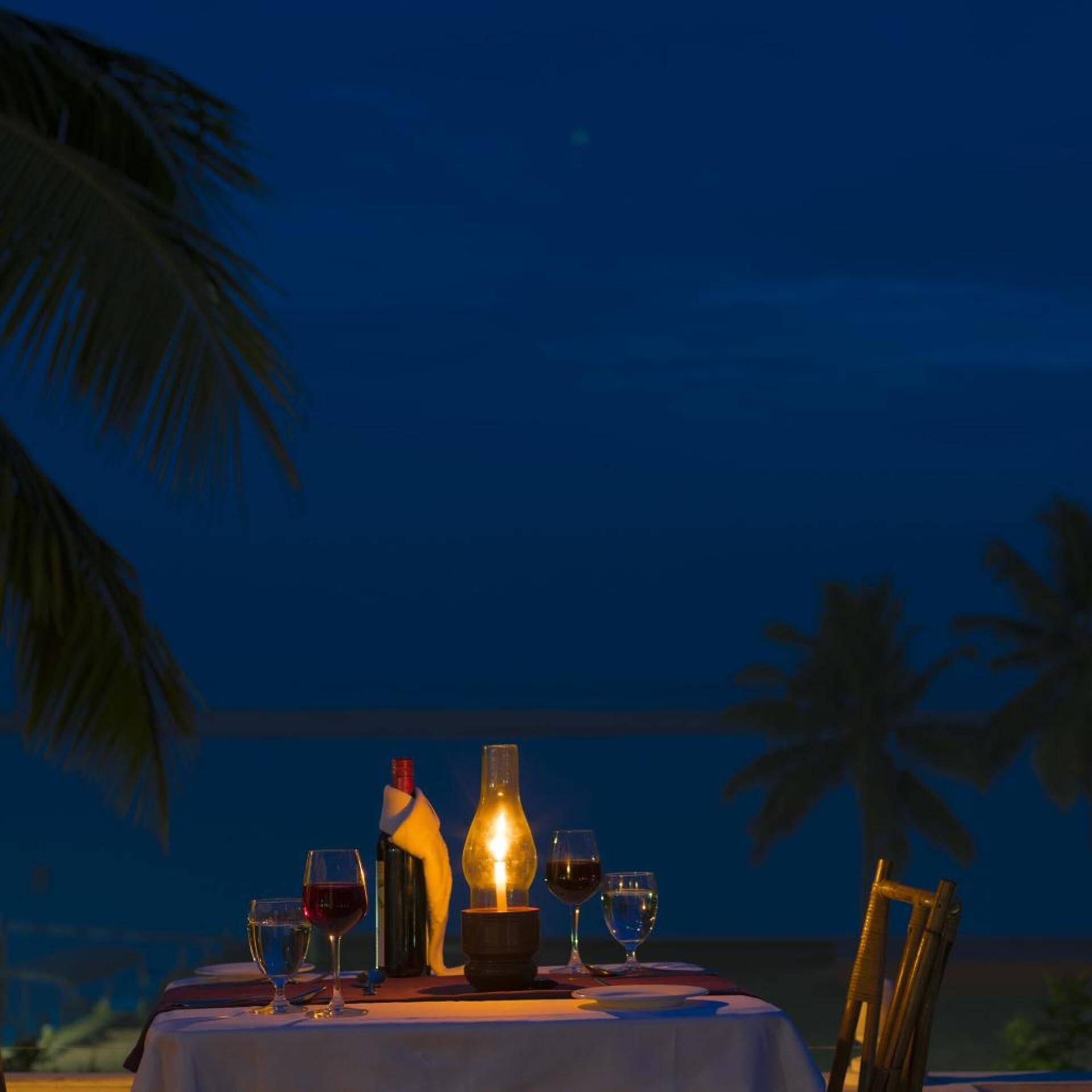 A table set for dining with a bottle and glasses, outdoors at night.