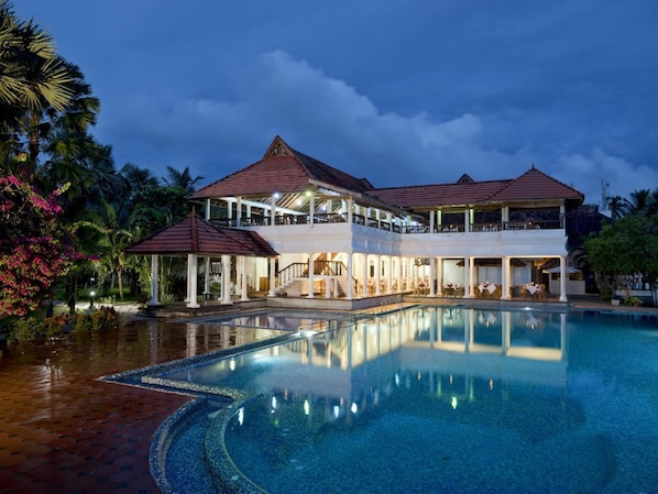 A resort with a large pool, multiple dining areas, and a covered outdoor seating area.