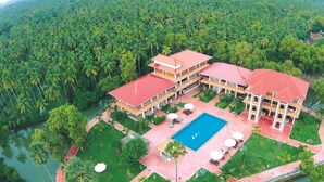 A large hotel with multiple buildings, a swimming pool, and lush greenery surrounding it. - Isola di Cocco Ayurvedic Beach Resort (Neyyattinkara)