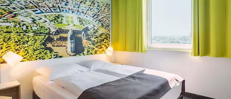A hotel room with a bed, a map mural, a window with curtains, and a nightstand.