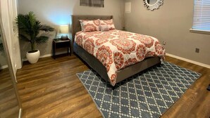 Un dormitorio con una cama, una mesita de noche, una planta en maceta y un espejo en la pared.