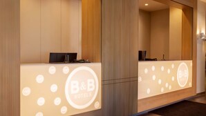 A reception desk with a logo, a phone, and a computer. - B&B Hotel Kiel-Wissenschaftspark (Kiel)