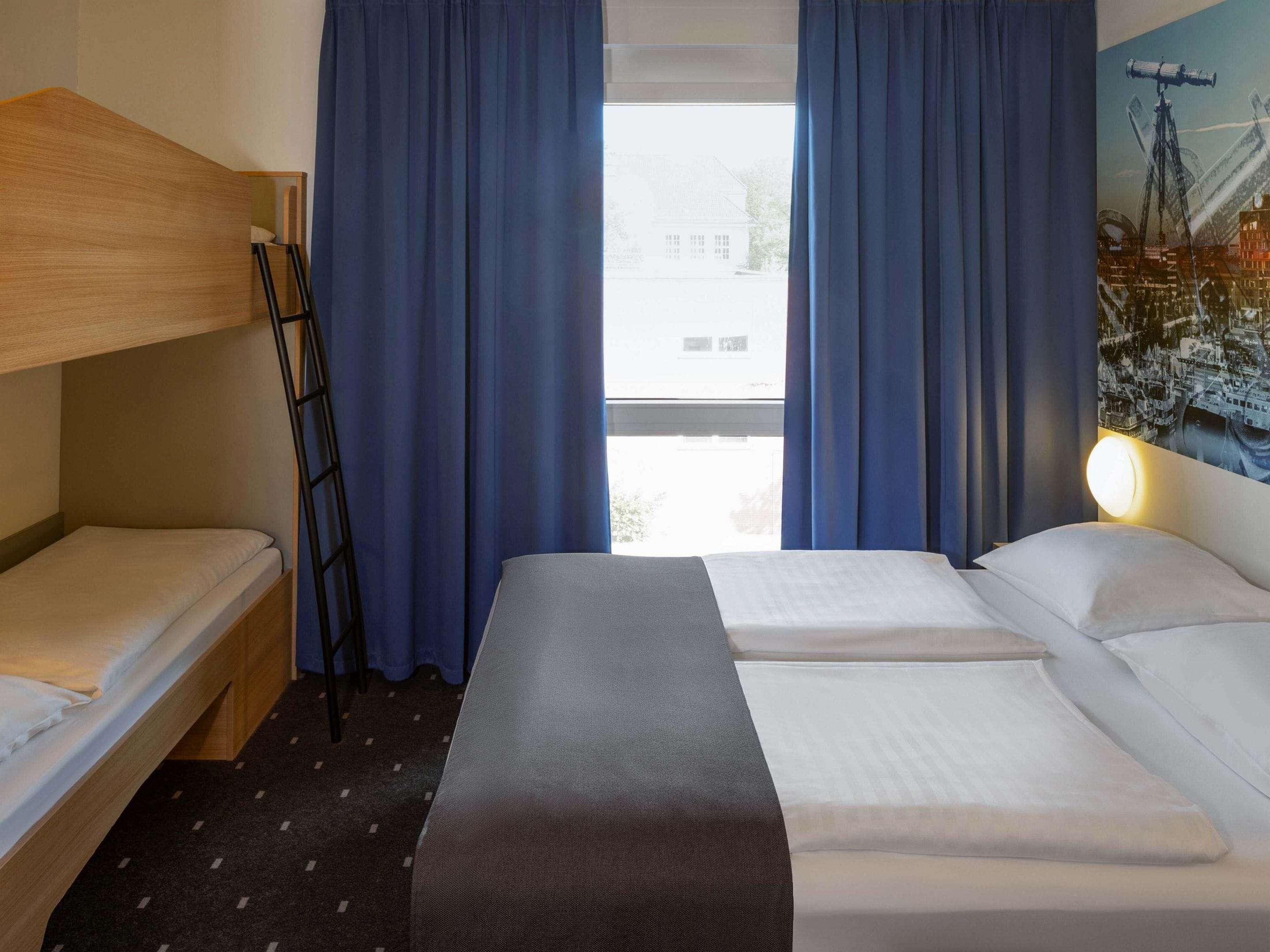 Habitación de hotel con literas, una cama individual y una ventana con cortinas.