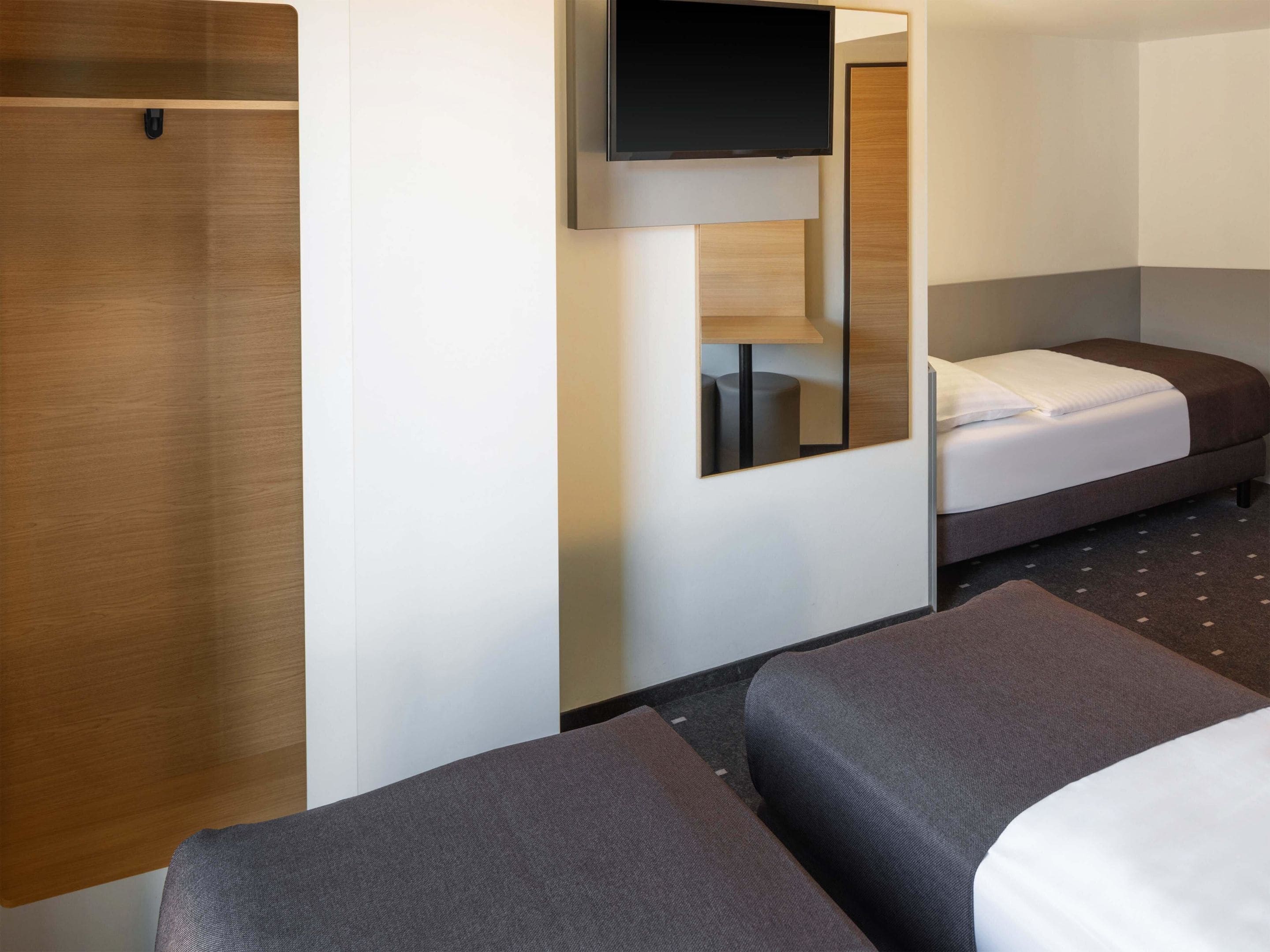 Ein Hotelzimmer mit Bett, Sofa, Fernseher und Spiegel.