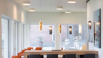 A modern conference room with a long table, multiple chairs, and pendant lighting.
