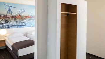 Habitación de hotel con cama, armario de madera y un mural de paisaje urbano en la pared.