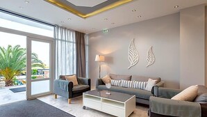A modern hotel lobby with a sofa, a coffee table, and a lamp. - Astris Sun (Thasos)