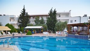 A swimming pool with lounge chairs and a covered seating area. - Astris Sun (Thasos)