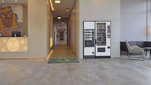 A hotel reception area with a vending machine, a reception desk, and a seating area. - B&B HOTEL Köln-Ehrenfeld (Cologne)