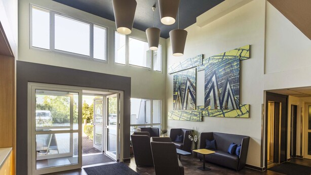 Eine moderne Lobby mit Empfangsschalter, einer Sitzecke und großen Fenstern.
