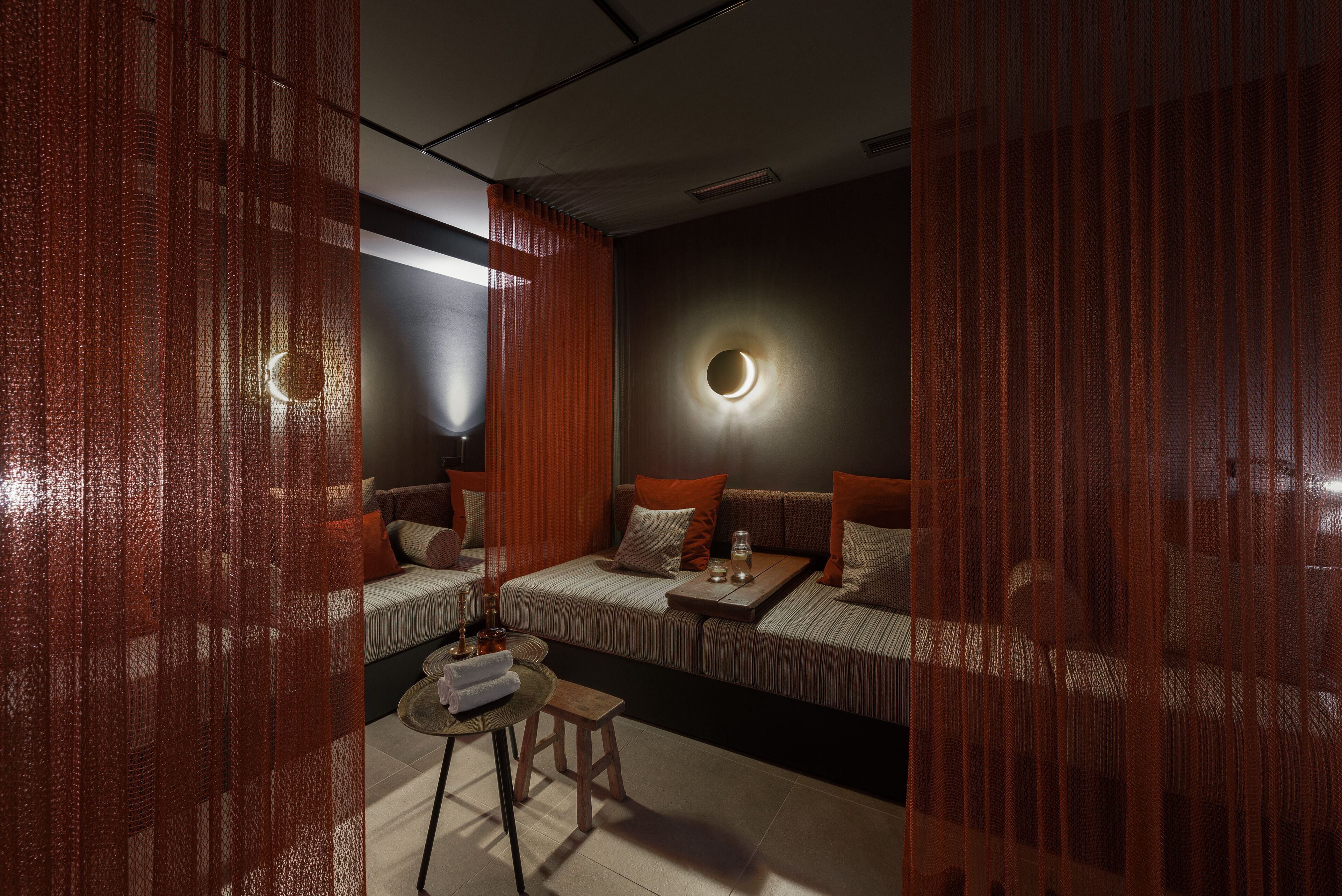 Una habitación de hotel moderna con un conjunto de sofás, una mesita y una lámpara de pared redonda.