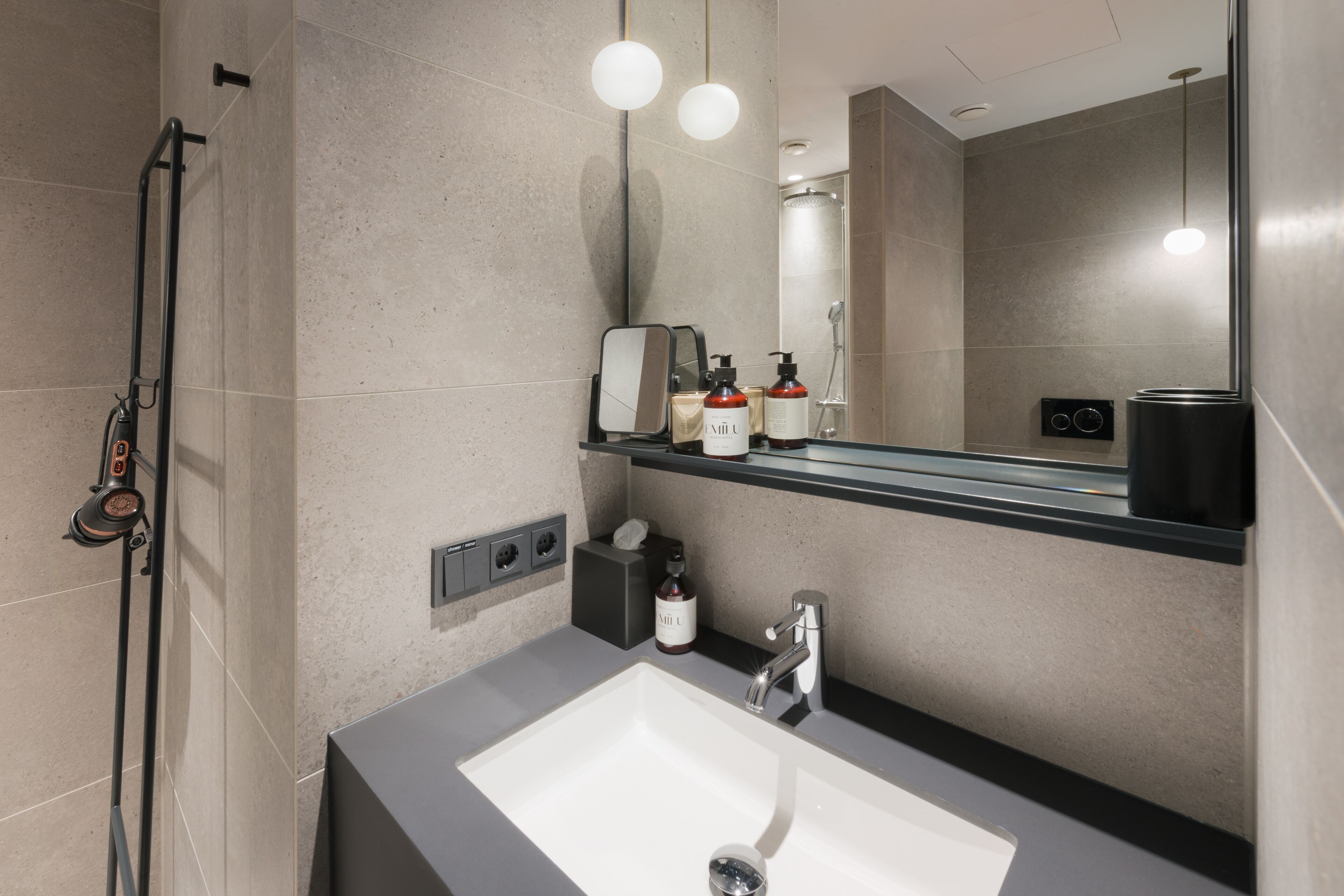 Ein modernes Badezimmer mit einem großen Spiegel, einem Waschbecken und einer Dusche.