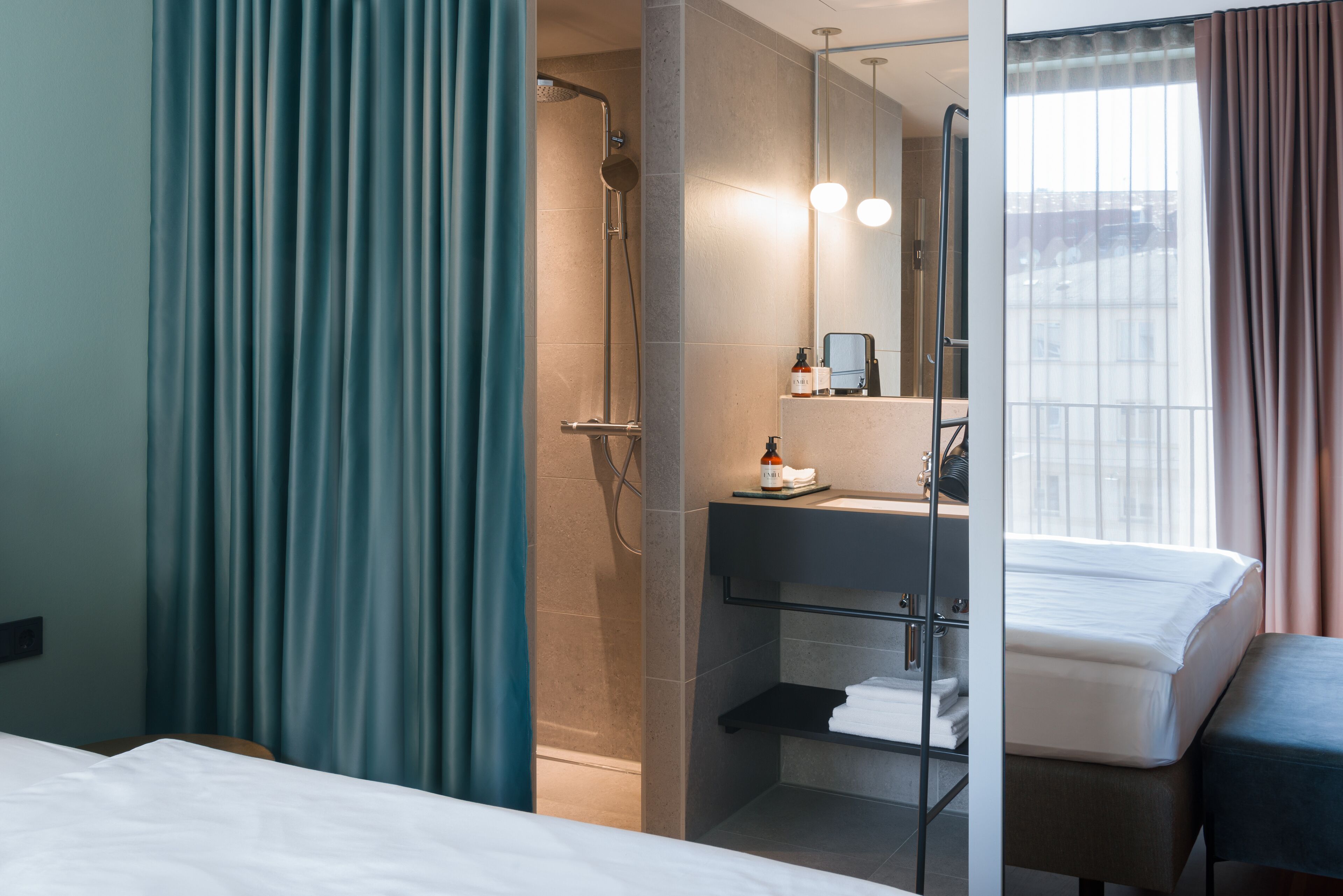Et moderne hotelværelse med bruser, håndvask, spejl og seng.