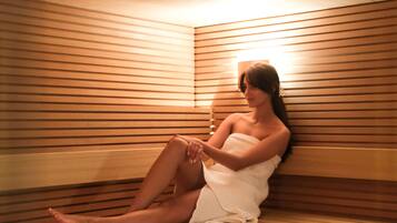Une personne assise dans un sauna en bois, doté de bancs à lattes.
