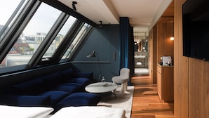 Un interior moderno con un sofá azul, una mesa de centro redonda y un televisor montado en una pared de madera.
