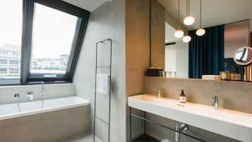 Ein modernes Badezimmer mit einer Badewanne, einem großen Spiegel und einem Waschtisch.