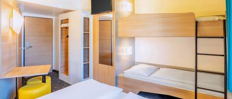 A hotel room with a bunk bed, a desk, a chair, and a wardrobe.