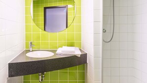 Un baño con lavamanos, espejo y ducha.