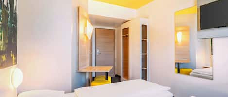 Une chambre d’hôtel avec deux lits, une télévision, un miroir et une armoire.