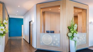 Un área de recepción de hotel con diseño moderno, que incluye un mostrador de recepción, una pared azul y un mostrador de recepción de madera.