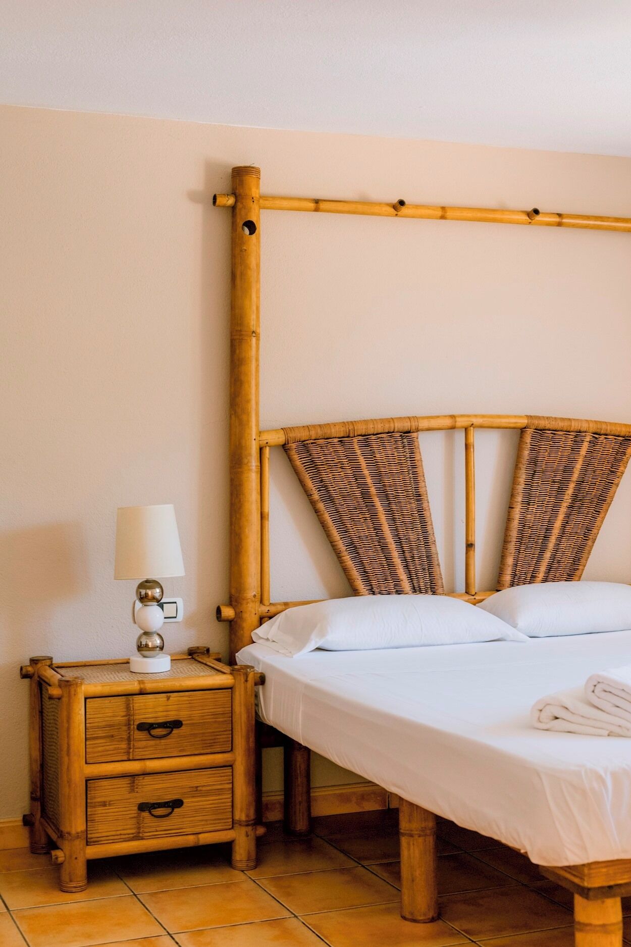 Una stanza con un letto, un comodino con una lampada e un comò in legno.