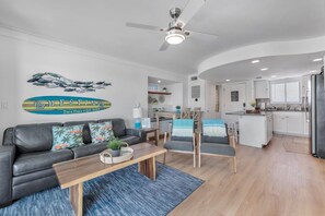 A modern living room with a sofa, chairs, a coffee table, and a ceiling fan.