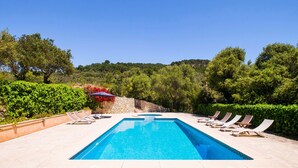 A rectangular swimming pool with lounge chairs and a stone wall in the background. - Natural Stone Villa with Pool: Villa Son Reus (Felanitx)